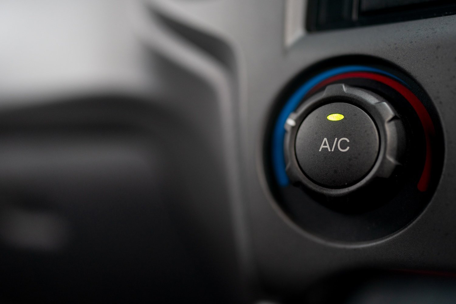 Botón de aire acondicionado A/C en consola de vehículo — control de climatización automotriz